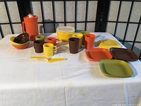 Photo of all kids Tupperware pieces on a white cloth with black folding screen background.