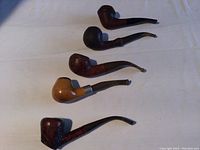 Top-down view of all five tobacco pipes showing varied shapes and finishes.