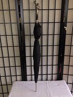 Full length photo of closed black umbrella showing pointed metal tip and sculpted knight bust handle.