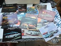 Multiple brochures spread out, showing various car models mostly Pontiac 1970s models with colorful exterior and interior images.