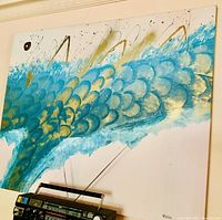 Photo of large abstract fish tail canvas painting showing blue and gold colors with black and white accents.
