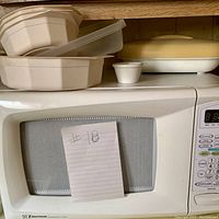 White Emerson microwave oven with digital keypad and display, note attached with '#18'