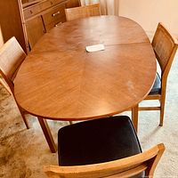Full view of oval dining table with four chairs arranged around it