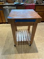 Front view showing butcher block top, legs and lower slatted shelf