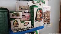 Shelf display showing boxed Department 56 Christmas in the City lighted houses and accessories with original packaging.
