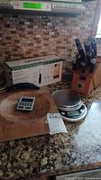 Overview showing knife block with knives, Cuisinart box, cutting board, timer and scale