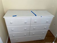 Full view of the white painted wood dresser showing all seven drawers and overall shape.