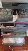 Mesh drawer with folded and rolled fabrics in various colors and patterns including florals and geometric prints.