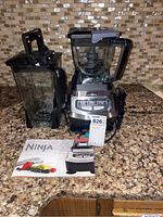 Ninja Blender set with two pitchers and user guide booklet displayed on counter.