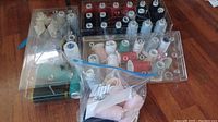 Clear plastic storage boxes with various sized sewing threads in different colors including black, red, white, and teal.