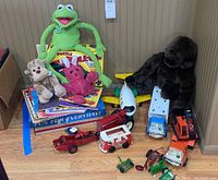 Full lot showing plush toys, toy vehicles, and children's books arranged on the floor.