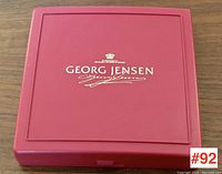 Closed red box with Georg Jensen logo and signature embossed on lid