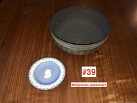 Overview of both Wedgwood Jasperware pieces, black bowl and small blue plate side by side on wooden surface