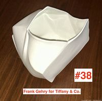 Front view of white crumpled-form vase on wood surface