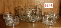 Full set of five clear glass salad bowls with floral textured pattern by Oiva Toikka for Iittala Finland, front view on wood background