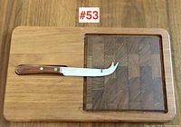 Top view of teak cheese board with square inset block wood section and cheese knife resting on the board.