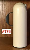 Front view of the vintage Rosti melamine carafe highlighting its cylindrical shape and grey handle against a wooden background.
