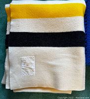 Folded Hudson's Bay Point Blanket showing yellow, white, and black horizontal stripes with visible label.