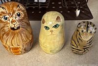 Photo shows set of 3 cat themed Russian nesting dolls, varying in size and painted with different cat fur patterns and expressions.