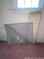 Photo showing two cutting mats and one wooden cutting board leaning against a wall, items used for sewing and quilting crafts.