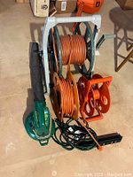 Lot items arranged on floor showing blower and reels with cords