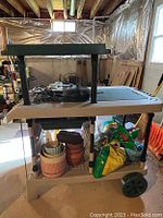 Gardening cart holding several bags of mulch/fertilizer and multiple flower pots underneath