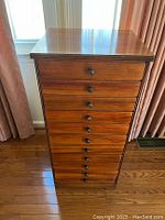Front view of the wooden sheet music chest with 11 drawers and round wooden knobs.