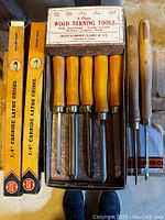 Photo of 5-piece wood turning tool set with wooden handles in original Montgomery-Ward & Co. box alongside assorted chisels with wooden handles.