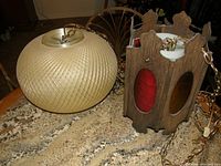 Two vintage swag lights on a granite surface: one plastic globe lamp and one wood-framed stained glass lamp, with hanging chains.