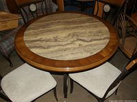 Round dining table with faux granite tabletop and four matching chairs with beige upholstered seats