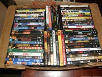Box containing 60 assorted DVD movies showing a variety of titles from genres like drama, action, sci-fi and classics.