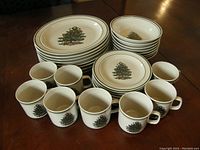 Full view showing dinner plates, dessert plates, bowls, and coffee cups all featuring Christmas tree design, arranged on table.