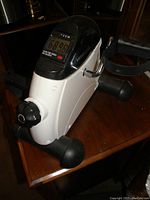 Under desk bicycle trainer showing digital display with exercise metrics and control knob.