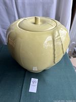 Front view of yellow apple shaped ceramic cookie jar showing overall shape and lid.