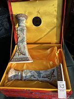 Pair of porcelain butterfly motif candlesticks arranged in silk-lined red storage case with yellow interior and coin medallion on lid.