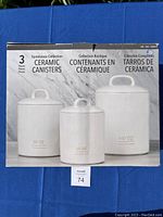 Box front showing three white ceramic canisters and their sizes 140 oz, 80 oz, 56 oz, labeled Farmhouse Collection.