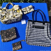 Photo showing all three bags on blue cloth background including two Vera Bradley floral quilted bags and one geometric patterned tote bag with matching accessories.