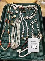 Full view of assorted pearl and white bead necklaces and bracelets on a green tray showing variety and quantity of items in the lot. Includes brooch and various bead sizes.