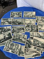 Photo of all 22 postcards laid out flat showing black and white interiors, classrooms, and exterior scenic views on a blue cloth background