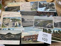 Photo showing a spread of 20 vintage postcards laid out, including colored and black-and-white images featuring buildings and landscapes.
