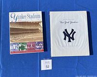 Two hardcover Yankees anniversary books on blue background, showing front covers clearly.