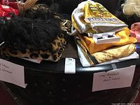 Two stacks of outfits and hats on a table with handwritten labels indicating 'Cave Man and Cave Woman' and 'Ms Peanut and Beer Man'.