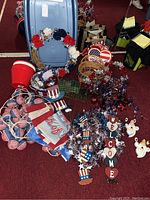 Photo showing assorted 4th of July decorations including wreath, garland, flags, yard stakes, 'Welcome' sign, and baskets inside a large plastic tub.