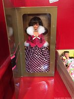 Avon exclusive Barbie doll in original box with clear window showing Barbie in red and black checkered dress with fur trim around collar and cuffs.