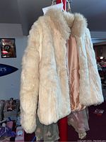 Full view of the cream-colored fur coat revealing the texture and style