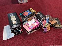Lot of 14 assorted VHS tapes stacked showing various titles and some VHS cassettes without sleeves.