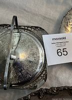 Top view of silver plated butter dish lid and base showing ornate engravings, glass insert visible through base