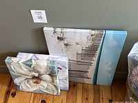 Four canvas artworks arranged against wall, showing white magnolia and pier print