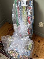 A plastic bag containing multiple rolls of gift wrap paper including Christmas and seasonal patterns, along with gift bags.