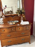 Front view of antique tiger oak dresser with mirror, showing carved details and original hardware.
